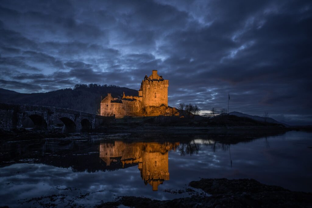 Le château d’Eilean Donan illuminé au bord d’un loch en Écosse, l’un des châteaux les plus emblématiques du pays.